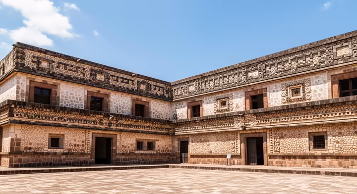 An Aztec noble's palace (tecpan) with two stories, built from reddish tezontle stone and decorated with intricate carvings.